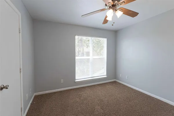 an empty room with a window and a fan