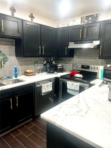 a kitchen with kitchen island granite countertop a sink stainless steel appliances and cabinets