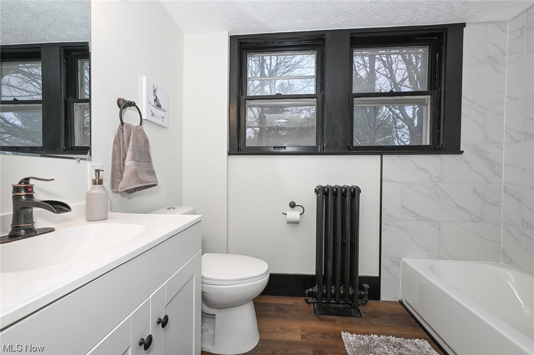 232 Randolph Road Mogadore, OH 44260 - Photo 25 of 35 Full bathroom featuring a textured ceiling, vanity with extensive cabinet space, hardwood / wood-style floors, radiator heating unit, and toilet
