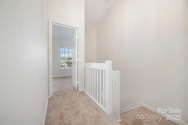 a view of a hallway with wooden floor and a bathroom