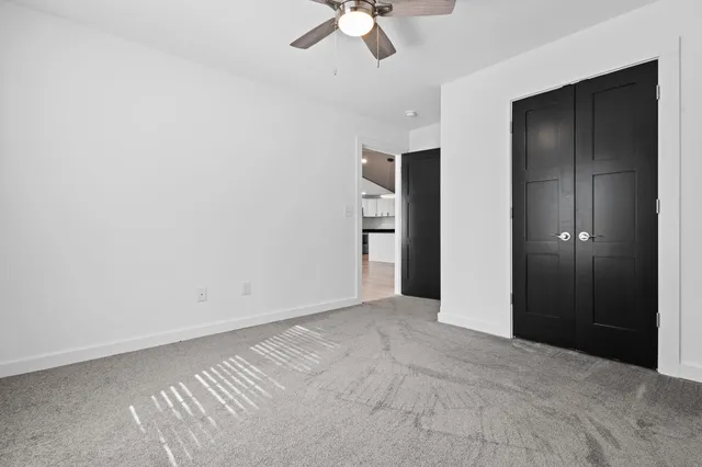 an empty room with closet and a ceiling fan