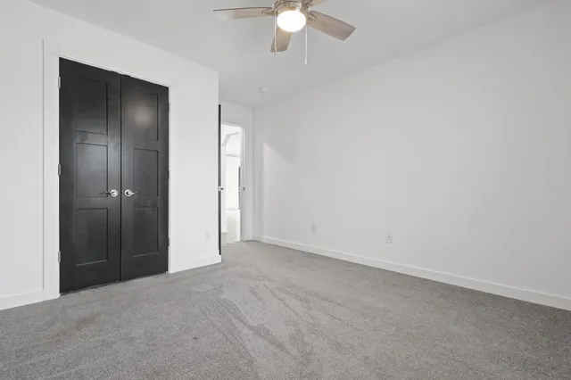 an empty room with a ceiling fan and closet area