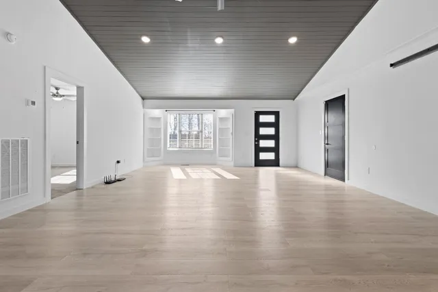 an empty room with wooden floor and windows
