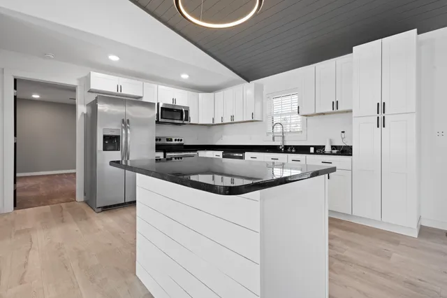 a kitchen with kitchen island a sink stainless steel appliances and cabinets