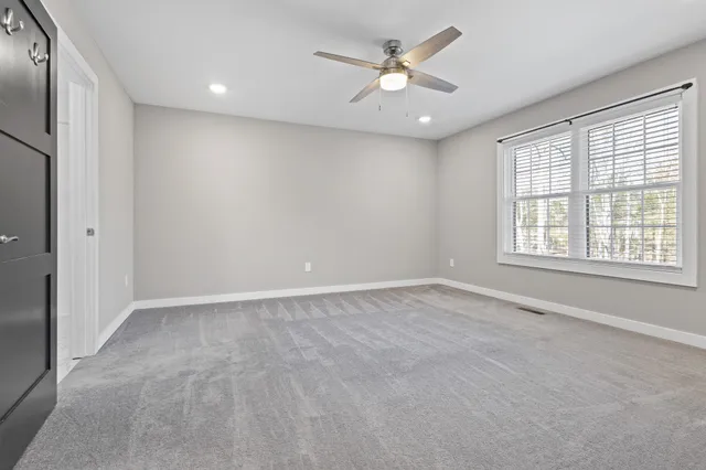 an empty room with windows and ceiling fan