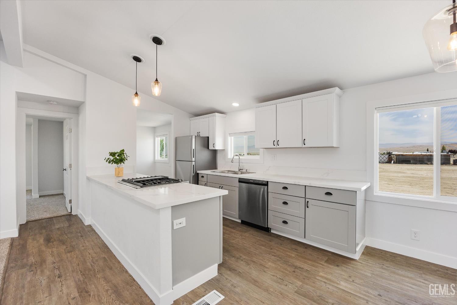 Undisclosed Address Taft, CA 93268 - Photo 23 of 40 a kitchen with granite countertop a sink stove a refrigerator and white cabinets with wooden floor