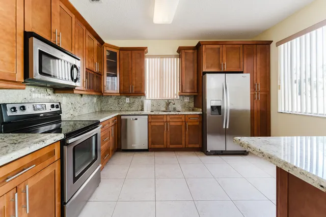 a kitchen with stainless steel appliances granite countertop a stove top oven a sink dishwasher and a refrigerator