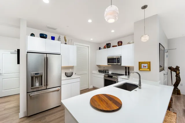 a kitchen with a refrigerator a stove and a sink with wooden floor