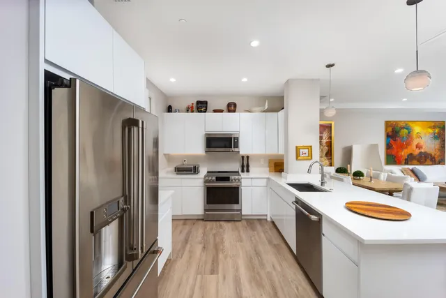 a kitchen with stainless steel appliances a refrigerator a stove a sink and a oven with wooden floor