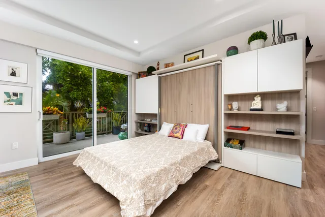 a bedroom with a bed a large window with table and chairs