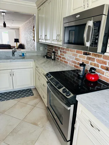 a kitchen with granite countertop a stove top oven microwave and cabinets