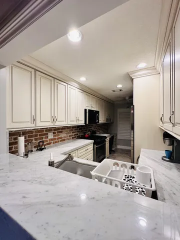 a kitchen with stainless steel appliances granite countertop a stove top oven a sink a dining table and chairs with wooden floor