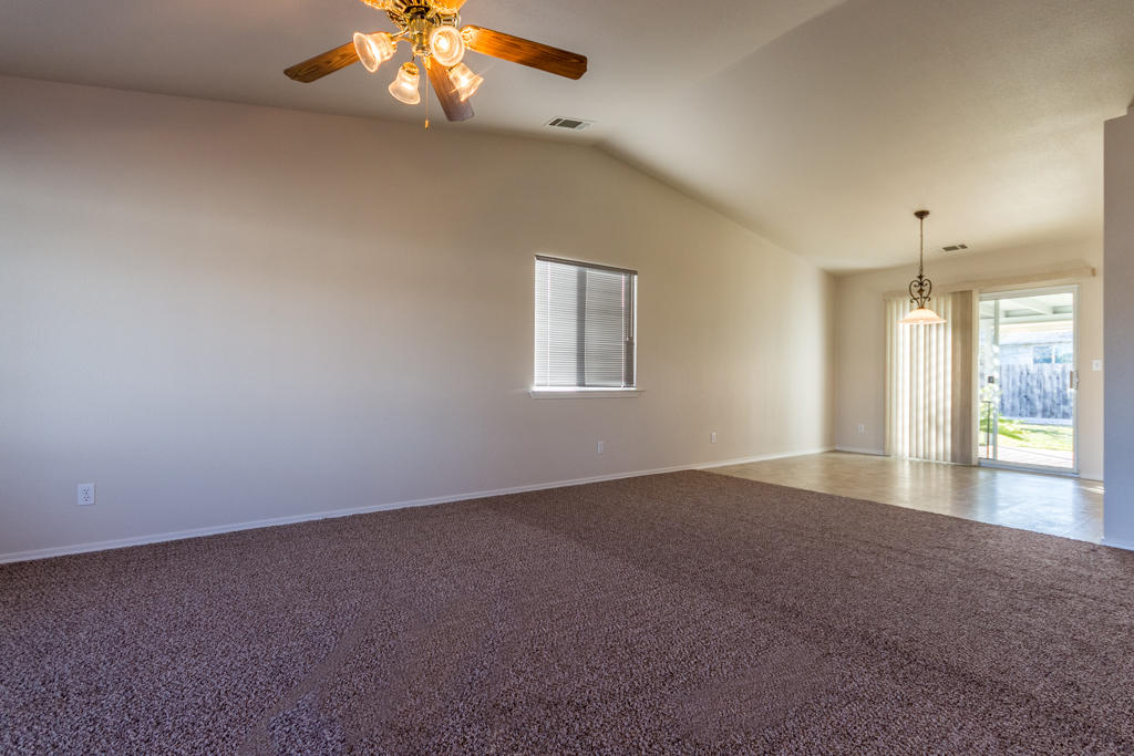11380 Puffin Way Redding, CA 96003 - Photo 2 of 27 an empty room with a chandelier fan and windows