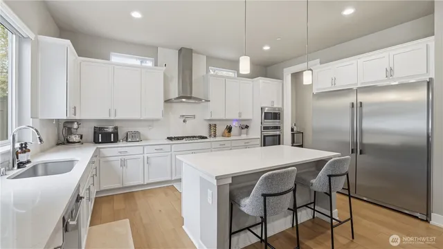 a kitchen with stainless steel appliances granite countertop a white cabinets and a refrigerator