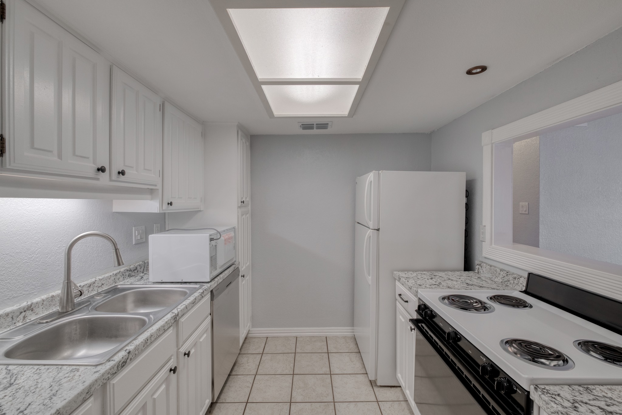 8210 Bent Tree Road, Unit 153 Austin, TX 78759 - Photo 12 of 20 Kitchen featuring white cabinetry with dark hardware, granite-look countertops, and a double stainless steel sink with a gooseneck faucet