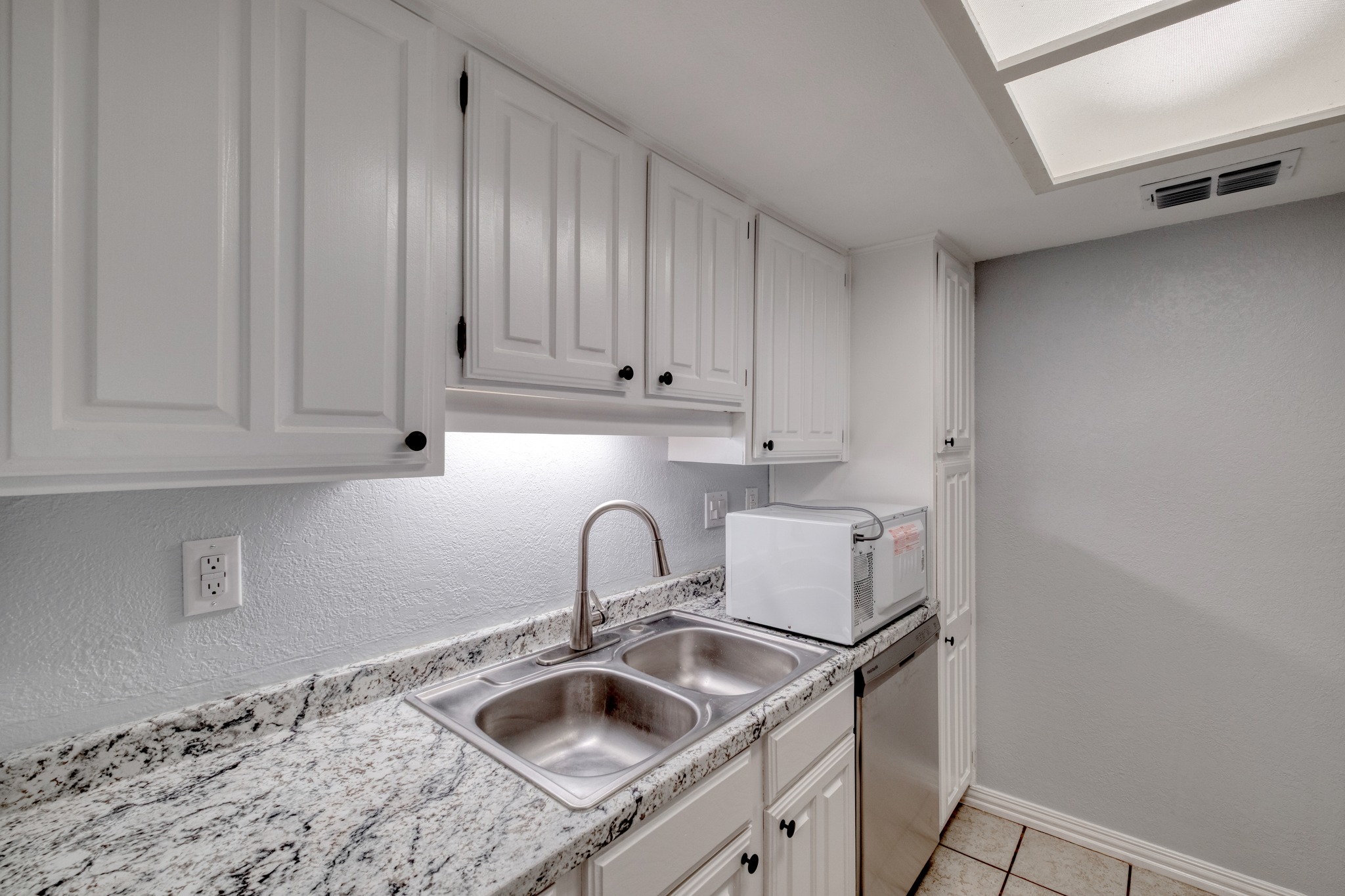 8210 Bent Tree Road, Unit 153 Austin, TX 78759 - Photo 13 of 20 Kitchen featuring white paneled cabinetry, a double basin stainless steel sink, patterned stone countertops, and a full-size stainless steel dishwasher