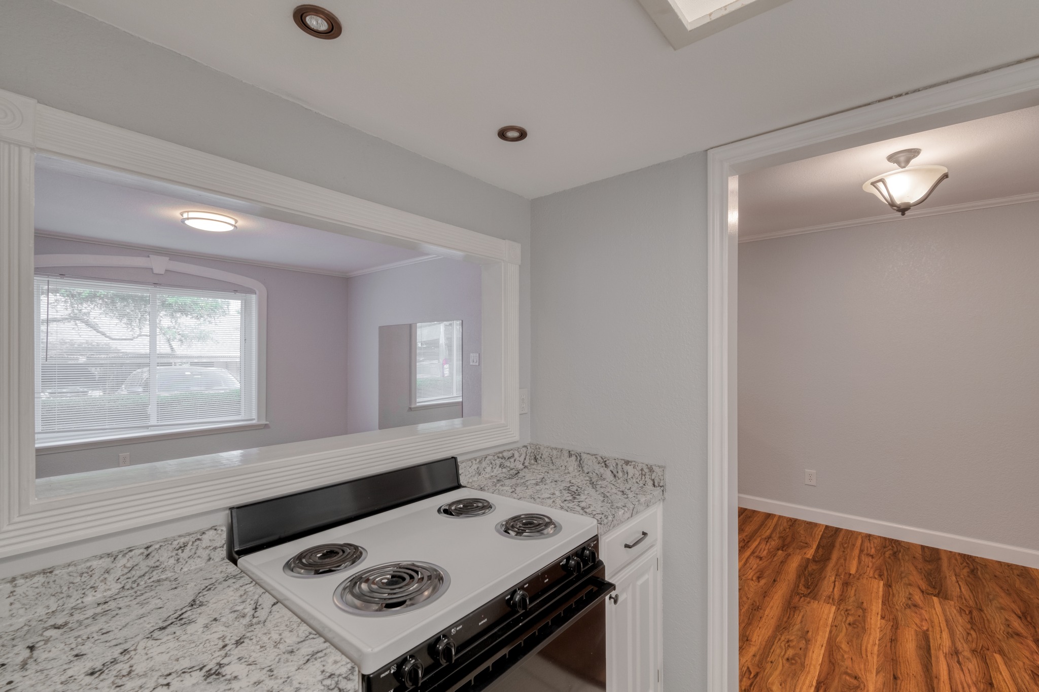 8210 Bent Tree Road, Unit 153 Austin, TX 78759 - Photo 14 of 20 Kitchen featuring a built-in electric range with a black oven, light-toned granite countertops, and white cabinetry