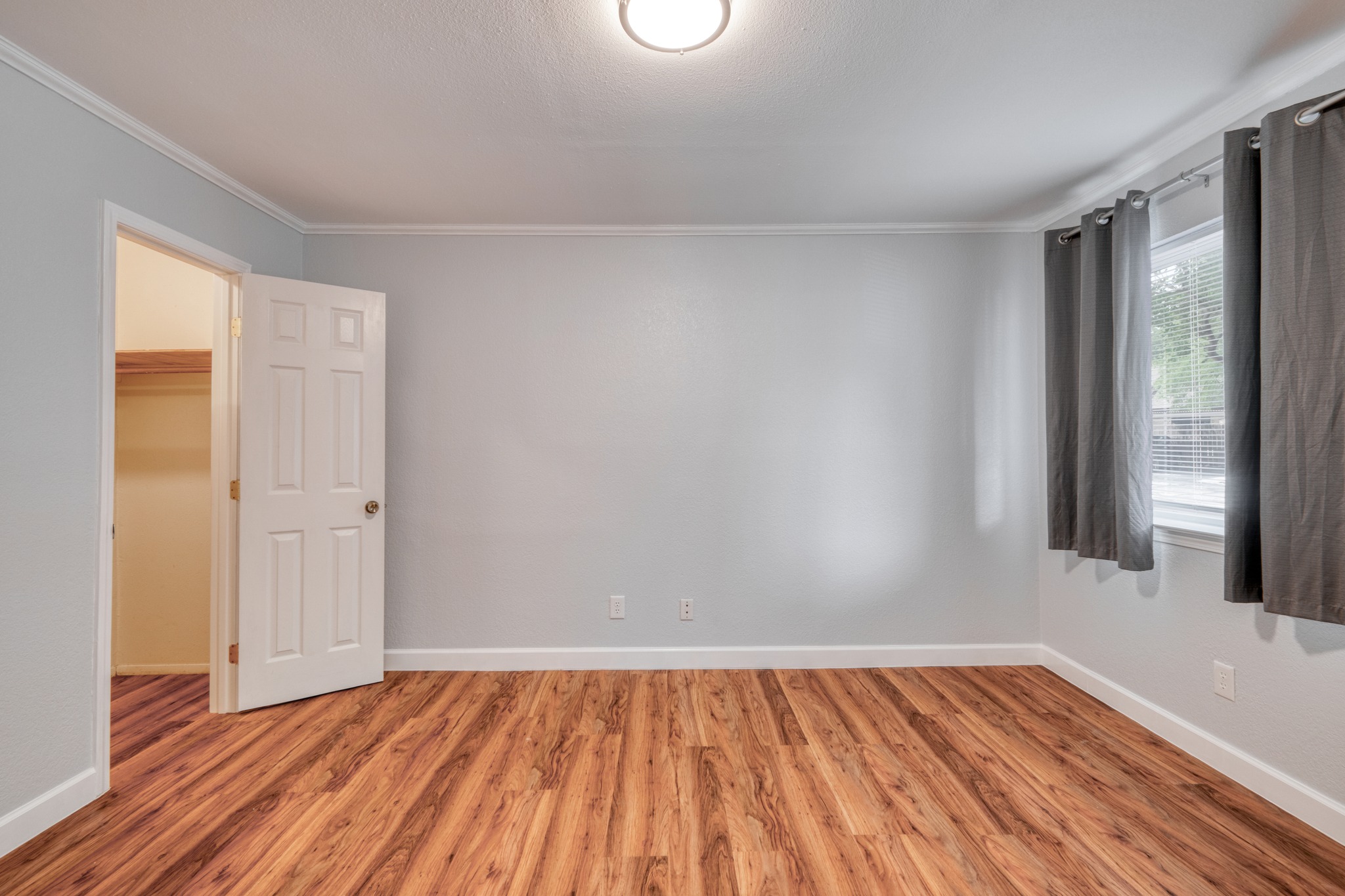 8210 Bent Tree Road, Unit 153 Austin, TX 78759 - Photo 16 of 20 Room featuring wood-finish flooring, light gray walls, a window with horizontal blinds, and a paneled door opening to a closet with a built-in shelf