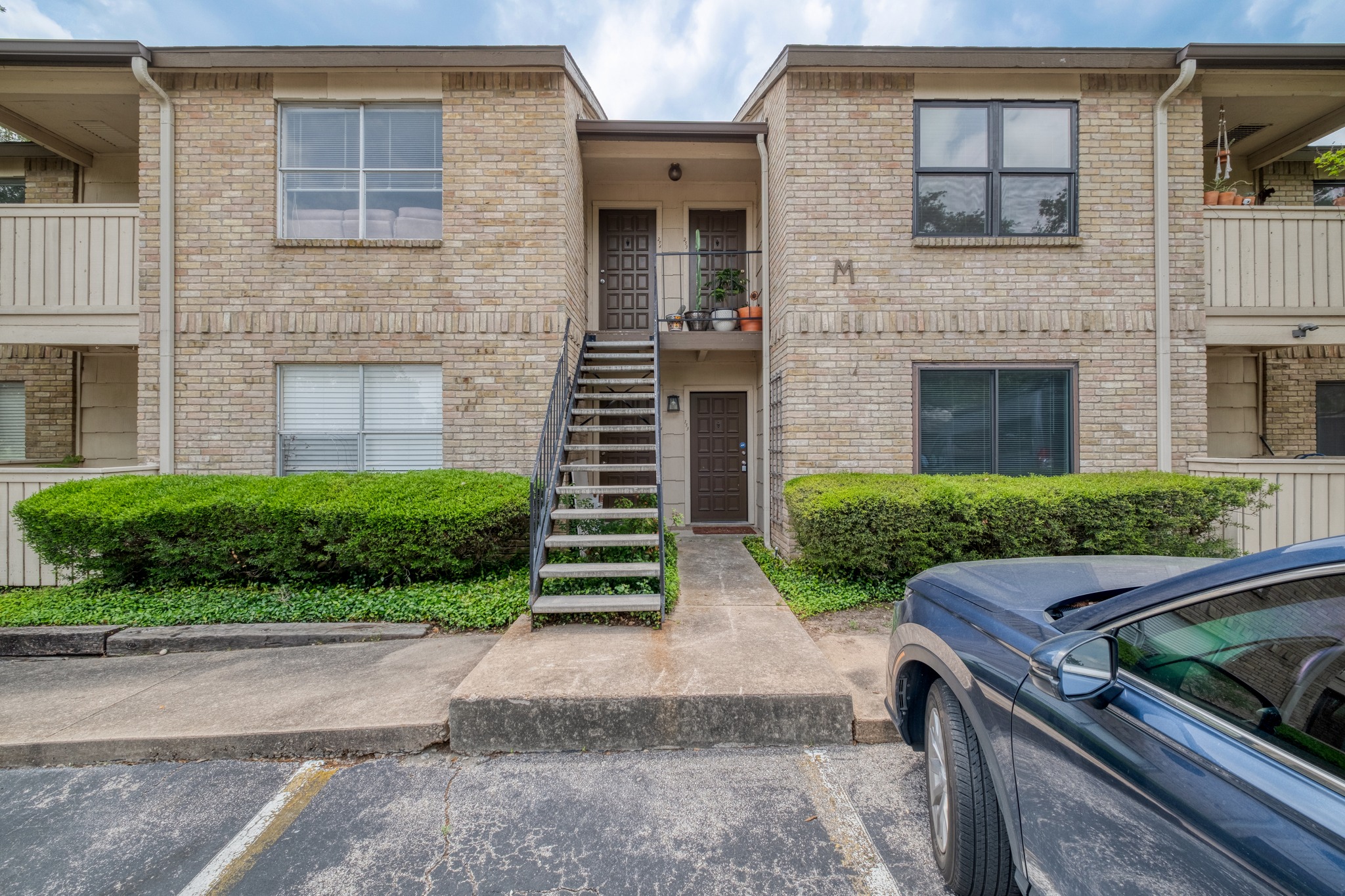 8210 Bent Tree Road, Unit 153 Austin, TX 78759 - Photo 3 of 20 Two-story brick exterior building featuring a central exterior staircase with metal handrails