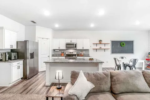 a living room with stainless steel appliances furniture and a view of kitchen