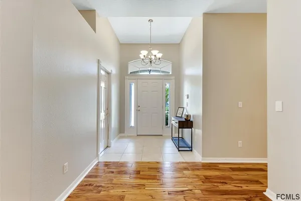 a view of a hallway with wooden floor and a chandelier