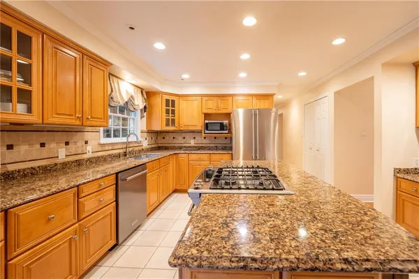 a large kitchen with kitchen island granite countertop a large window and stainless steel appliances