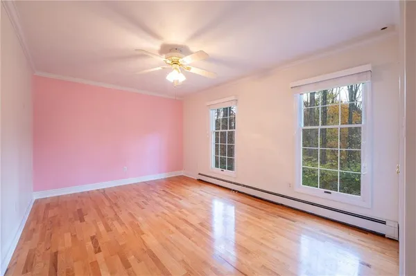 a view of an empty room with a window and wooden floor