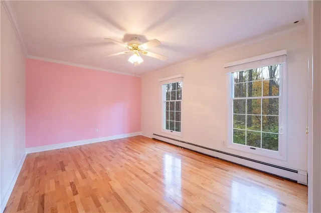 a view of an empty room with a window and wooden floor