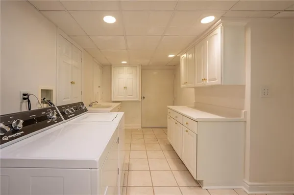 a large white kitchen with a sink and dishwasher a stove top oven with white cabinets