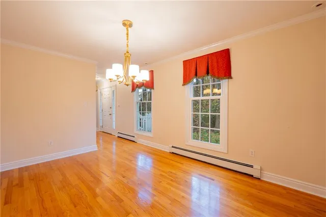 a view of a room with wooden floor chandeliers and kitchen view
