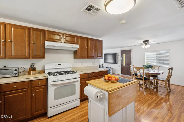 a kitchen with a stove a sink dishwasher and white cabinets with wooden floor