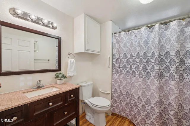 a bathroom with a granite countertop sink toilet and mirror