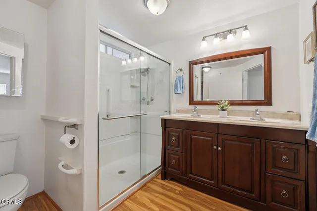 a bathroom with a double vanity sink toilet mirror and shower