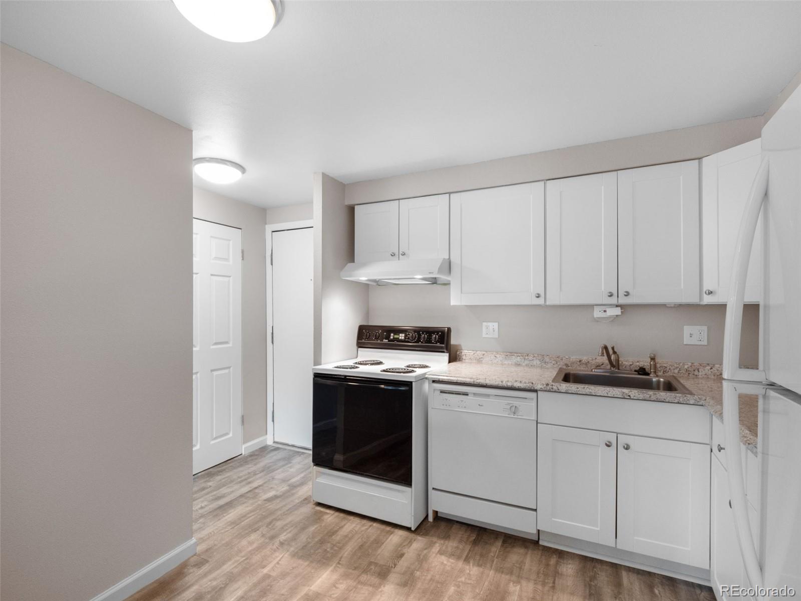 1304 South Parker Road, Unit 146 Denver, CO 80231 - Photo 3 of 22 a kitchen with granite countertop white cabinets and white appliances