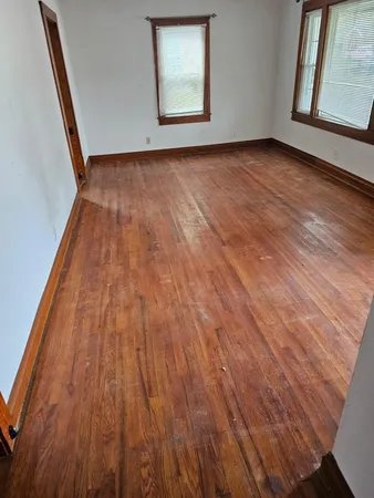 a view of an empty room with wooden floor and a window