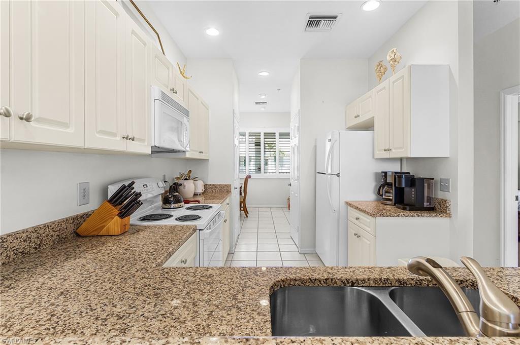 7910 Mahogany Run Lane, Unit 1225 Naples, FL 34113 - Photo 11 of 42 a kitchen with stainless steel appliances granite countertop a sink dishwasher stove and refrigerator with granite countertops