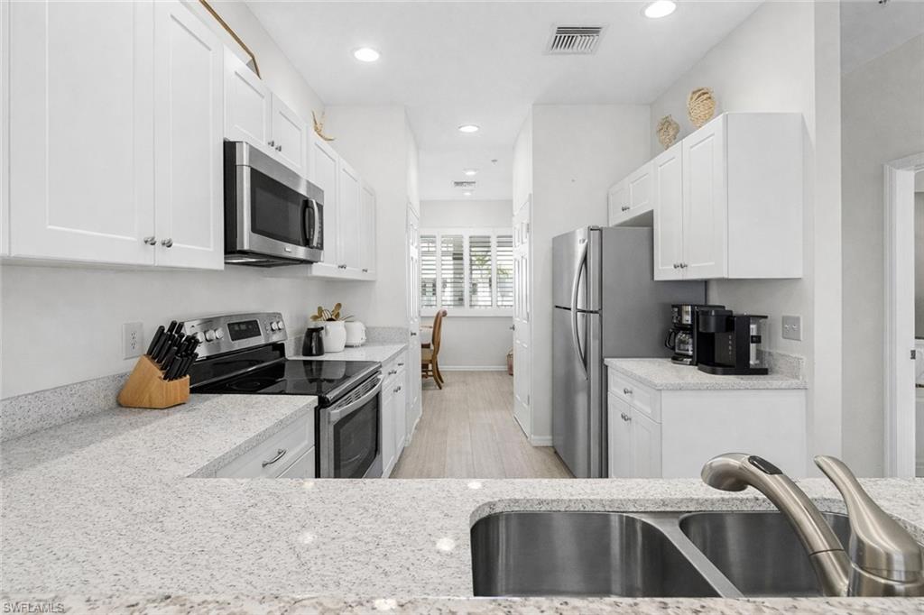 7910 Mahogany Run Lane, Unit 1225 Naples, FL 34113 - Photo 13 of 48 a kitchen with stainless steel appliances a stove a sink a refrigerator a stove a microwave and cabinets