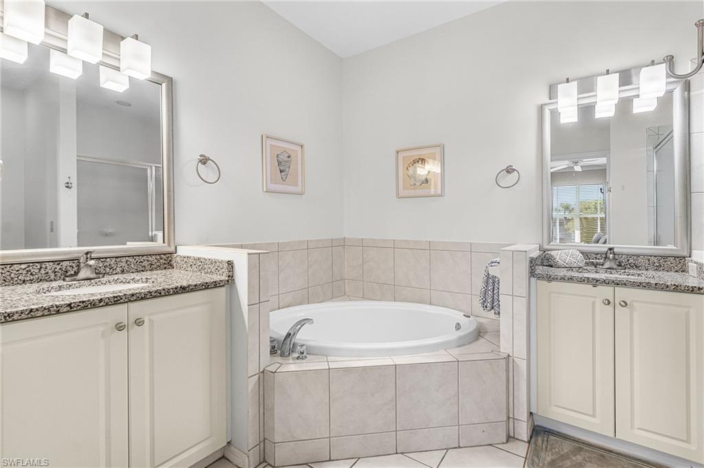 7910 Mahogany Run Lane, Unit 1225 Naples, FL 34113 - Photo 14 of 42 a bathroom with a granite countertop bathtub a sink and a window