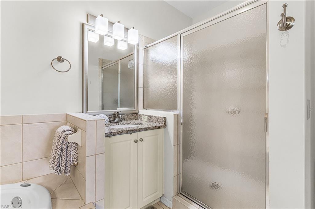 7910 Mahogany Run Lane, Unit 1225 Naples, FL 34113 - Photo 15 of 42 a bathroom with a granite countertop shower sink and mirror