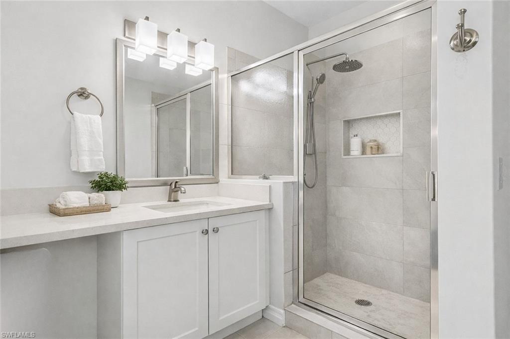 7910 Mahogany Run Lane, Unit 1225 Naples, FL 34113 - Photo 21 of 48 a bathroom with a shower sink and mirror