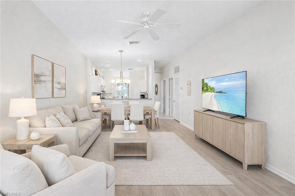 7910 Mahogany Run Lane, Unit 1225 Naples, FL 34113 - Photo 3 of 48 Virtual staged living area featuring a ceiling fan, light wood-style floors, and hanging lights