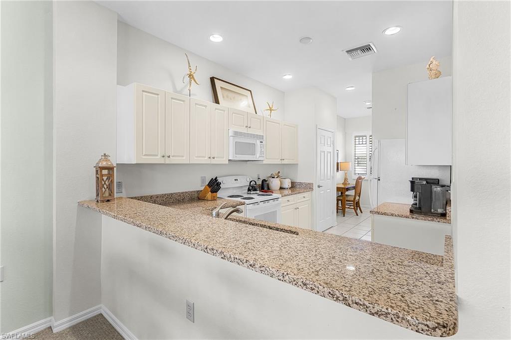 7910 Mahogany Run Lane, Unit 1225 Naples, FL 34113 - Photo 10 of 42 a view of a kitchen with kitchen island a sink appliances and a counter top space