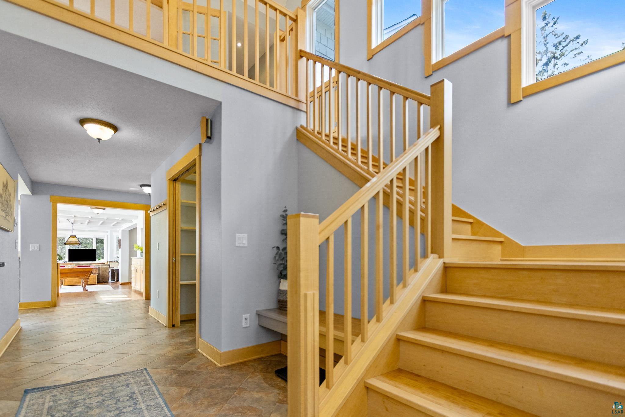 5163 Greenwood Road Duluth, MN 55804 - Photo 31 of 47 Spacious entry featuring a light wood staircase, coordinating wood trim, high ceilings, large windows, and tile flooring