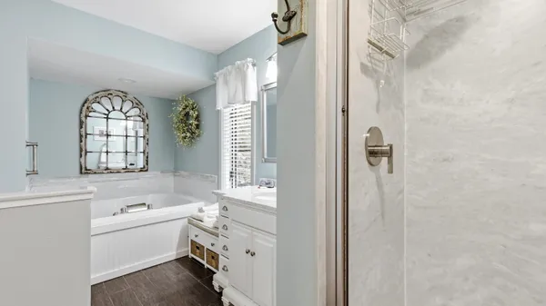 a bathroom with a granite countertop sink a mirror a vanity and a bathtub