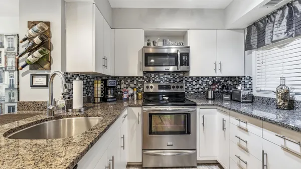 a kitchen with granite countertop a sink stainless steel appliances and cabinets