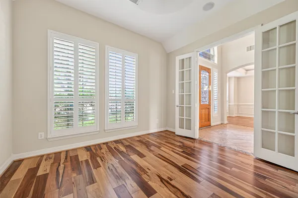 a view of an empty room with wooden floor and a window