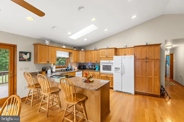 a view of a kitchen with kitchen island granite countertop a refrigerator and wooden floor