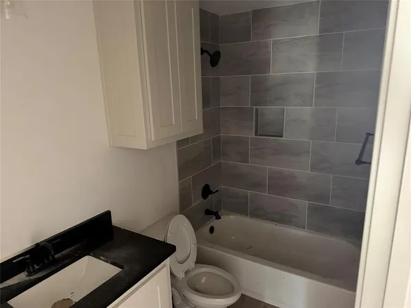 a bathroom with a granite countertop sink toilet and bathtub