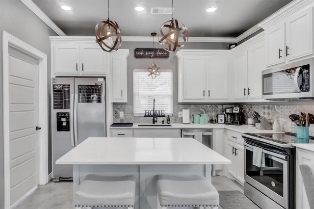a kitchen with cabinets a sink stainless steel appliances and dining table