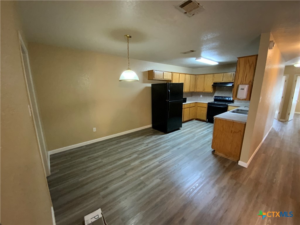 2602 Edgefield Street, Unit B Killeen, TX 76549 - Photo 4 of 12 a view of a room with wooden floor kitchen stove and windows